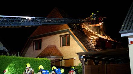 Einsatzkräfte der Feuerwehr stehen auf einer Feuerwehrleiter und löschen einen Brand in Marzahn.