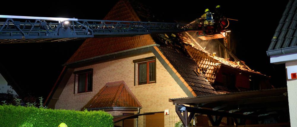 Einsatzkräfte der Feuerwehr stehen auf einer Feuerwehrleiter und löschen einen Brand in Marzahn. (Archivbild)