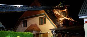 Einsatzkräfte der Feuerwehr stehen auf einer Feuerwehrleiter und löschen einen Brand in Marzahn.