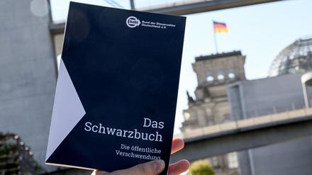 Das Schwarzbuch 2025/26 vom Bund der Steuerzahler Deutschland wird vor das Reichstagsgebäude gehalten. Das Schwarzbuch listet Beispiele auf, wo aus Sicht des Steuerzahlerbunds Steuergelder verschwendet wurden. 