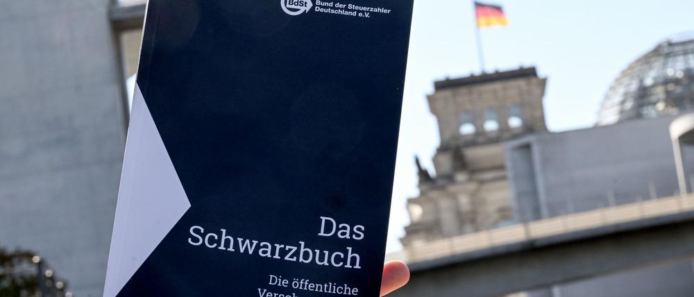 Das Schwarzbuch 2025/26 vom Bund der Steuerzahler Deutschland wird vor das Reichstagsgebäude gehalten. Das Schwarzbuch listet Beispiele auf, wo aus Sicht des Steuerzahlerbunds Steuergelder verschwendet wurden. 