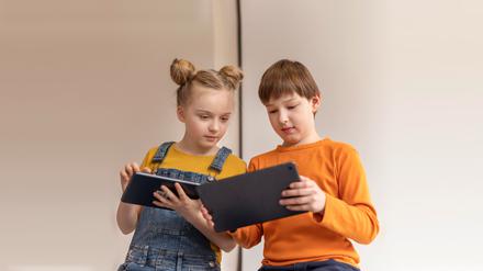 Ein Junge und ein Mädchen blicken auf ihre Tablets und lösen Aufgaben. Ziel sollte sein, dass Kinder kritisch und selbstständig lernen.