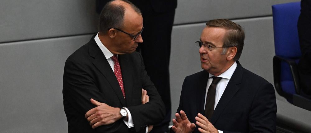 German Chancellor Friedrich Merz (L) chats with German Defence Minister Boris Pistorius  at the Bundestag during a general debate on budget, in Berlin on September 17, 2025. (Photo by RALF HIRSCHBERGER / AFP)