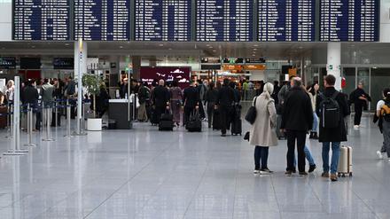 Passagiere stehen vor einer Anzeigetafel im Terminal 2 am Flughafen München. 
