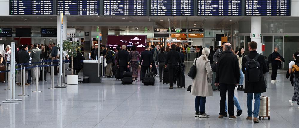 Passagiere stehen vor einer Anzeigetafel im Terminal 2 am Flughafen München.