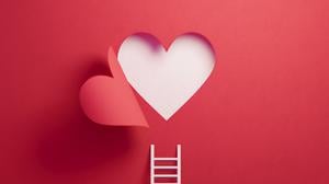 White ladder leaning on red wall with cut out heart shape. Horizontal composition with copy space.