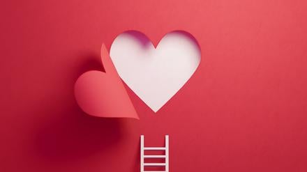 White ladder leaning on red wall with cut out heart shape. Horizontal composition with copy space.