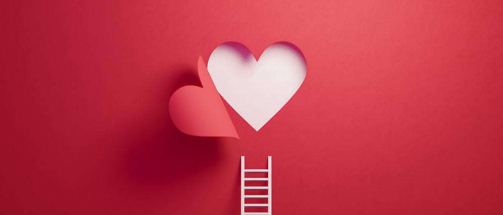White ladder leaning on red wall with cut out heart shape. Horizontal composition with copy space.
