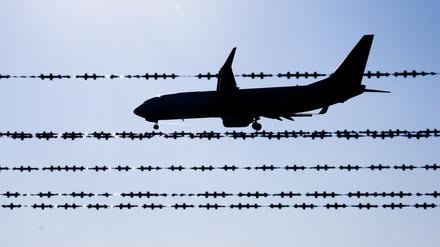 Ein Flugzeug fliegt hinter Stacheldraht am Flughafen Hannover.