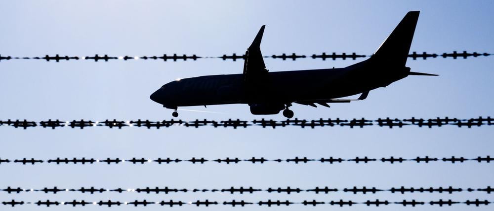 Ein Flugzeug fliegt hinter Stacheldraht am Flughafen Hannover.