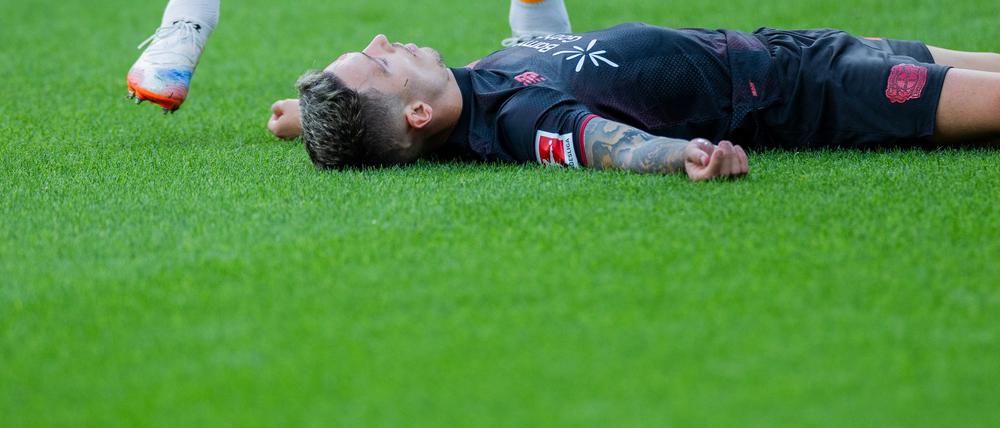 Bayer Leverkusens Kapitän Alejandro Grimaldo liegt nach einem Zusammenprall mit dem eigenen Mann benommen auf dem Boden. 