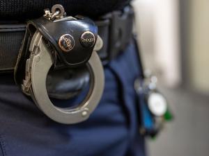 Eine Handschelle hängt am Gürtel eines Polizisten.