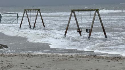 05.10.2025, Niedersachsen, Norderney: Wasser überflutet den Strand und umspülte Kinderschaukeln. Foto: Volker Bartels/dpa +++ dpa-Bildfunk +++