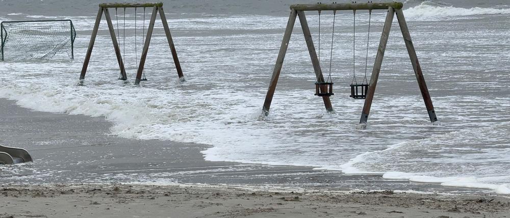 05.10.2025, Niedersachsen, Norderney: Wasser überflutet den Strand und umspülte Kinderschaukeln. Foto: Volker Bartels/dpa +++ dpa-Bildfunk +++