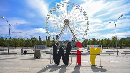 29.09.2020, Brandenburg, Potsdam: Die Buchstaben des Wortes „Wir“ stehen vor der Kulisse eines Riesenrades auf dem Stadtplatz Neuer Lustgarten im Gegenlicht der Sonne. 