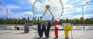 29.09.2020, Brandenburg, Potsdam: Die Buchstaben des Wortes „Wir“ stehen vor der Kulisse eines Riesenrades auf dem Stadtplatz Neuer Lustgarten im Gegenlicht der Sonne.