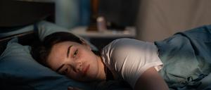 Eine junge Frau mit traurigem Gesichtsausdruck liegt im Bett (Symbolbild).