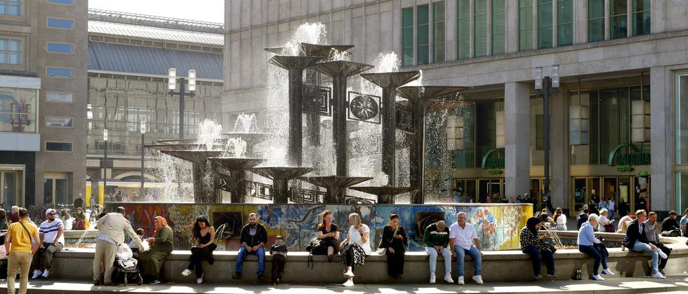 Menschen sitzen am Brunnen der Völkerfreundschaft am Alexanderplatz. (Symbolbild)