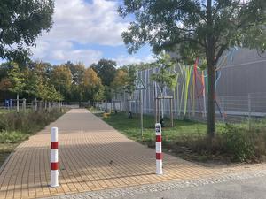 Der verpollerte Parkweg an der Werneuchener Wiese in Prenzlauer Berg, rechts im Bild die Schule, die als temporäre Schuldrehscheibe fungiert.
Foto: Patricia Wolf