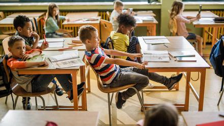 Playful boy having fun while swinging on a chair during a class at elementary school.