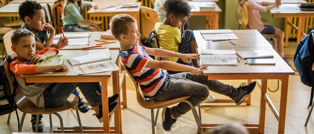 Playful boy having fun while swinging on a chair during a class at elementary school.