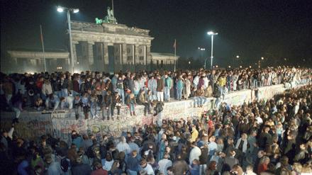 Menschen auf der Berliner Mauer vor dem Brandenburger Tor in der Nacht vom 9. auf den 10.11.1989.