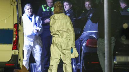 Beamtinnen der Spurensicherung stehen in ihren Spurensicherungsanzügen am Fahrzeug der KTU (Kriminaltechnische Untersuchung), im Hintergrund Polizeibeamte.