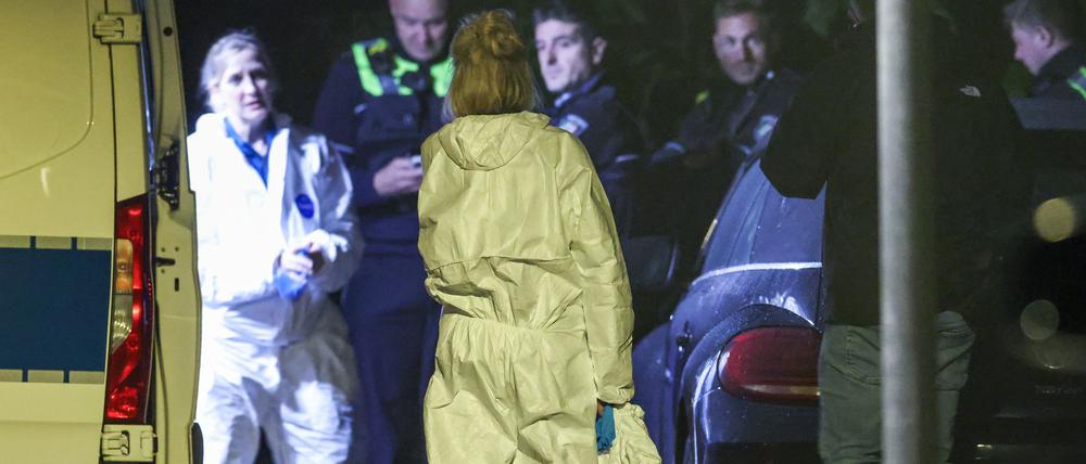 Beamtinnen der Spurensicherung stehen in ihren Spurensicherungsanzügen am Fahrzeug der KTU (Kriminaltechnische Untersuchung), im Hintergrund Polizeibeamte.
