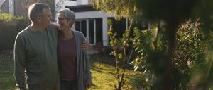 Ein lächelndes älteres Paar vor ihrem Eigenheim.