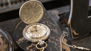 Eine Vintage-Uhr liegt aufgeklappt auf einem alten Holztisch.