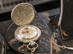 Eine Vintage-Uhr liegt aufgeklappt auf einem alten Holztisch.