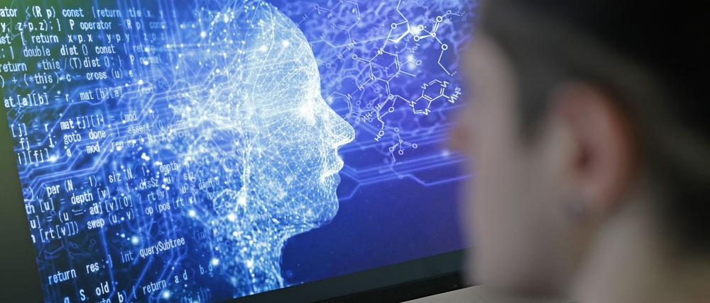 Ein Mann vor einem Bildschirm mit einem Kopf aus Daten (Symbolbild).