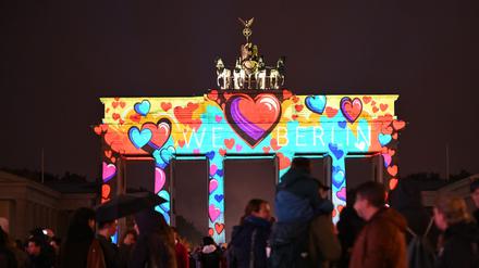 Trotz leichtem Regen stehen zahlreiche Schaulustige vor dem erleuchteten Brandenburger Tor.