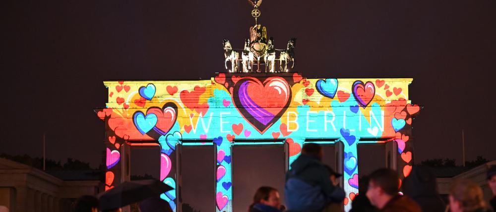 Trotz leichtem Regen stehen zahlreiche Schaulustige vor dem erleuchteten Brandenburger Tor.