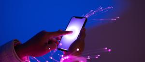 Hände streichen auf einem Handy-Display, Licht-Funken kommen heraus. Ein KI-generiertes Symbolbild für das Thema Digitalisierung.