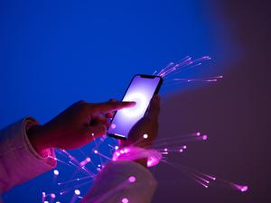 Hände streichen auf einem Handy-Display, Licht-Funken kommen heraus. Ein KI-generiertes Symbolbild für das Thema Digitalisierung. 