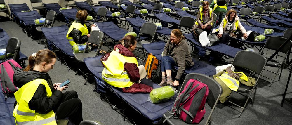 Freiwillige, die als Evakuierte an einer Übung für den Fall eines militärischen Konflikts teilnehmen, sitzen auf Stühlen und Betten in der Evakuierungsunterkunft, in der Sporthalle in Kaunas, Litauen.