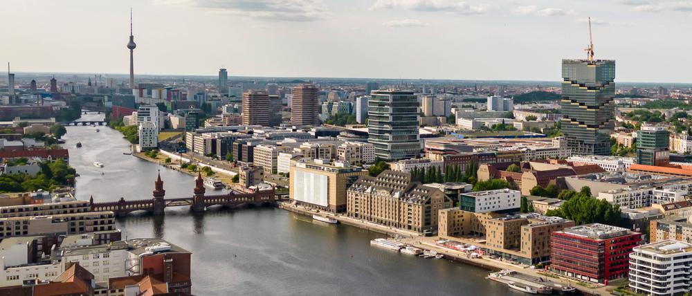 Drohenansicht auf die Berliner Spree mit dem Badeschiff unten, Amazon-Tower rechts und dem Fernsehturm oben.