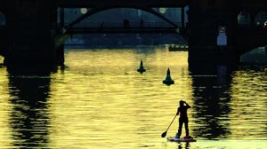 Eine Stehpaddlerin ist am Abend auf der Spree unweit der Oberbaumbrücke unterwegs. +++ dpa-Bildfunk +++