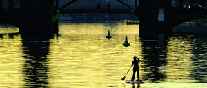 Eine Stehpaddlerin ist am Abend auf der Spree unweit der Oberbaumbrücke unterwegs. +++ dpa-Bildfunk +++