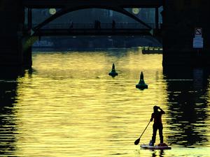 Eine Stehpaddlerin ist am Abend auf der Spree unweit der Oberbaumbrücke unterwegs. +++ dpa-Bildfunk +++