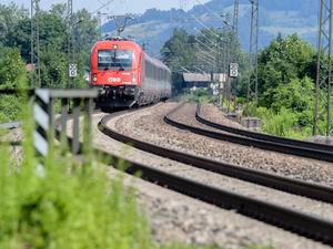 Ein Zug der Österreichischen Bundesbahnen (ÖBB) fährt über die Gleise der Bahntrasse durch das Inntal zwischen Rosenheim und Kufstein. 