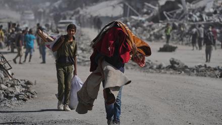 Vertriebene Palästinenser tragen ihre Habseligkeiten, während sie die stark beschädigte Al-Jalaa-Straße in Gaza-Stadt entlanggehen, nachdem Israel und die Hamas eine Pause in ihrem Krieg und die Freilassung der verbleibenden Geiseln vereinbart hatten. 