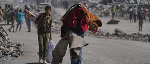 Vertriebene Palästinenser tragen ihre Habseligkeiten, während sie die stark beschädigte Al-Jalaa-Straße in Gaza-Stadt entlanggehen, nachdem Israel und die Hamas eine Pause in ihrem Krieg und die Freilassung der verbleibenden Geiseln vereinbart hatten.