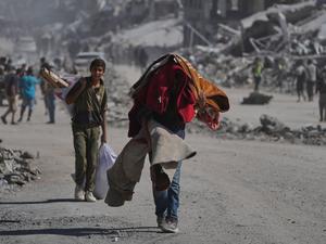 Vertriebene Palästinenser tragen ihre Habseligkeiten, während sie die stark beschädigte Al-Jalaa-Straße in Gaza-Stadt entlanggehen, nachdem Israel und die Hamas eine Pause in ihrem Krieg und die Freilassung der verbleibenden Geiseln vereinbart hatten. 