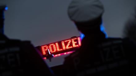 Polizisten stehen im Rahmen eines Fototermins vor einem Polizeifahrzeug (gestellte Szene).