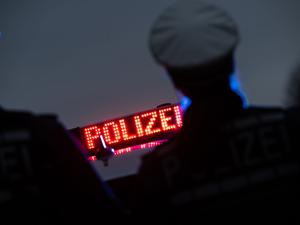Polizisten stehen im Rahmen eines Fototermins vor einem Polizeifahrzeug (gestellte Szene).