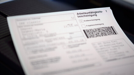  Eine Arbeitsunfähigkeitsbescheinigung liegt auf dem Drucker in einer Arztpraxis.