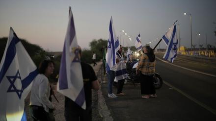 Menschen schwenken israelische Flaggen, als sie sich vor der Freilassung israelischer Geiseln, die im Gazastreifen festgehalten werden, vor einem Militärstützpunkt in der Nähe von Reim Area im Süden Israels versammeln.