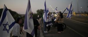 Menschen schwenken israelische Flaggen, als sie sich vor der Freilassung israelischer Geiseln, die im Gazastreifen festgehalten werden, vor einem Militärstützpunkt in der Nähe von Reim Area im Süden Israels versammeln.